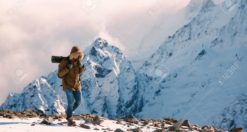66891033 man with backpack trekking in mountains cold weather snow on hills winter hiking